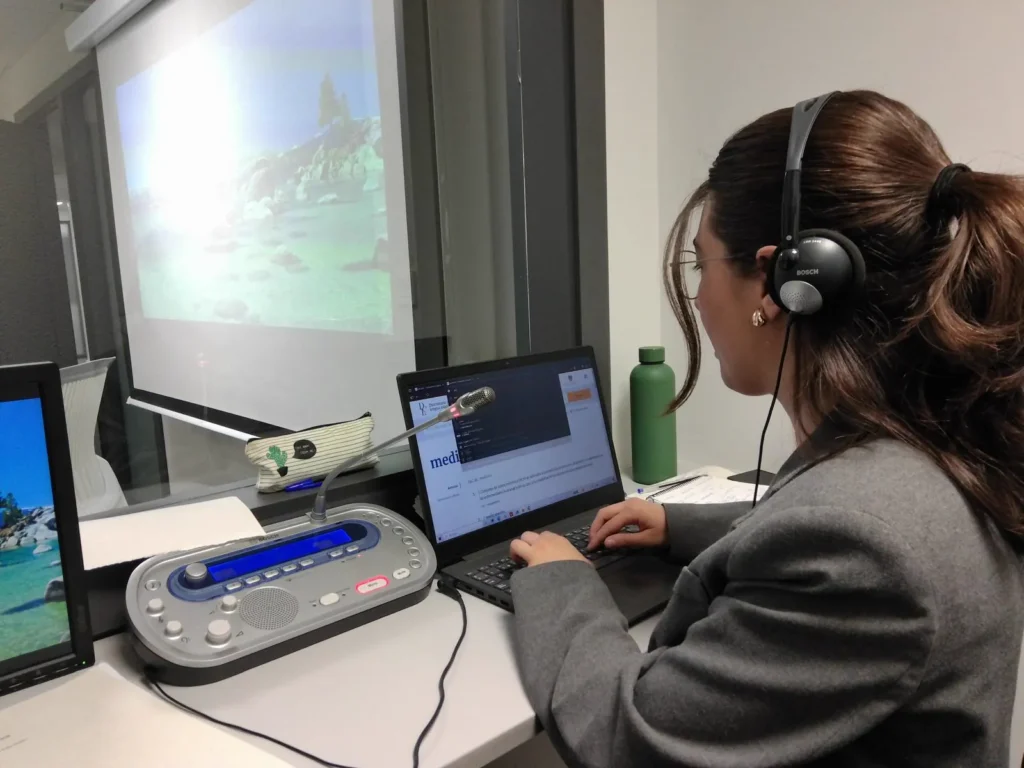 Raquel Ribera interpretando en simultánea desde una cabina de interpretación con consola y auriculares